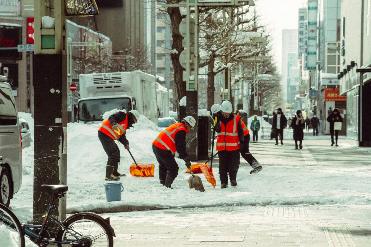 城市街道上有工人正在北海道日本清除積雪，拍攝於冬季